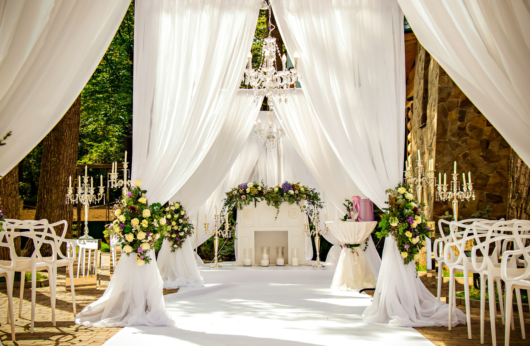 Draped wedding ceremony setup with chandeliers and florals